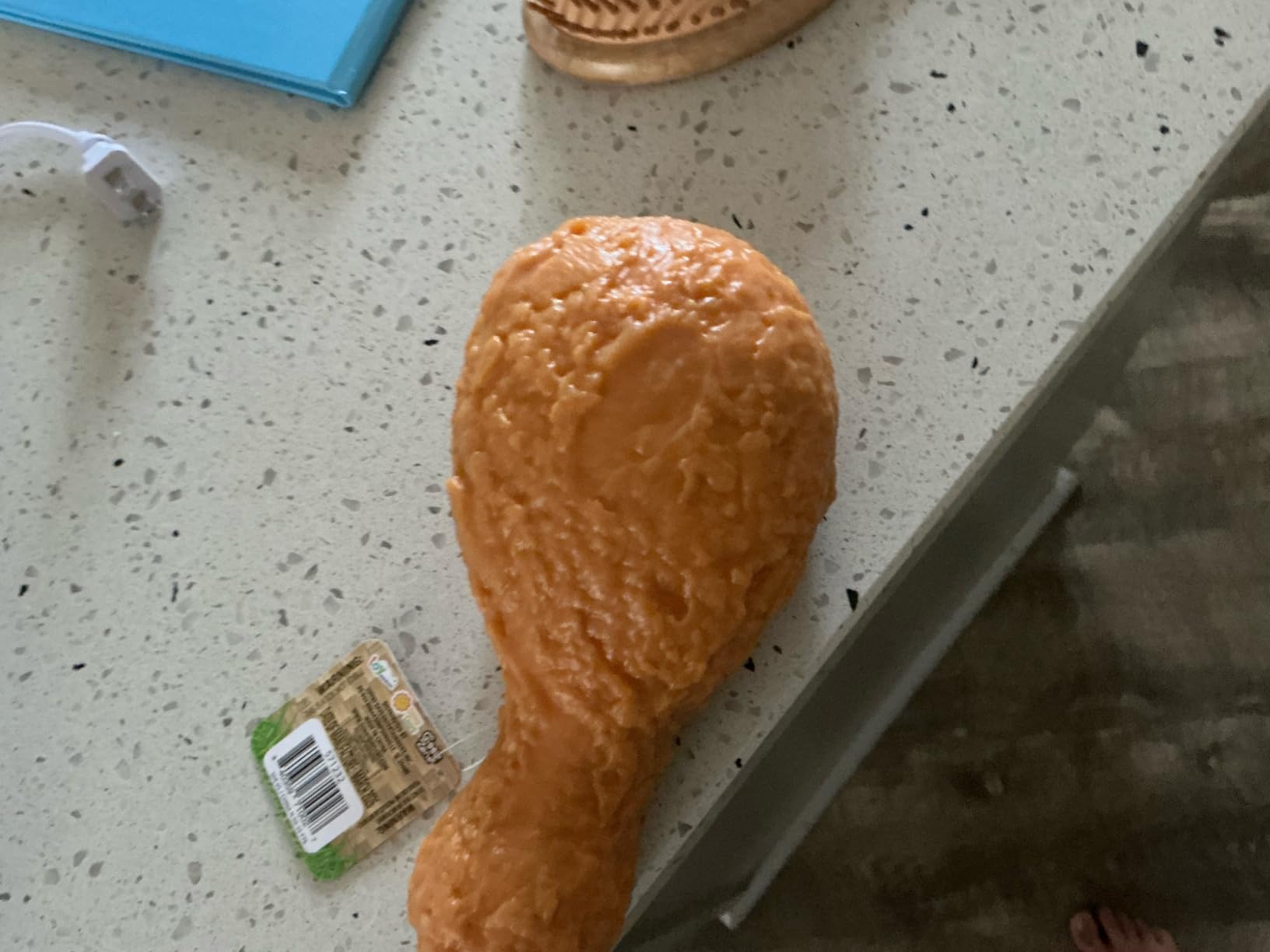 The Toymendous Squishy Fried Chicken drumstick on a speckled countertop with its hang tag still attached